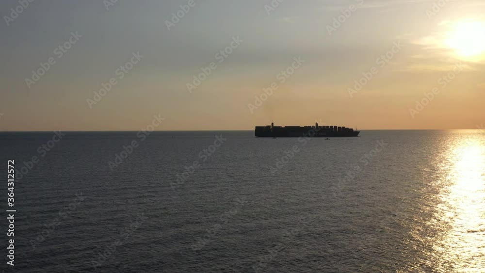 During sunset a Container cargo ship arriving in the harbor. Big container ship enters the port of Klang at the Klang delta, Malaysia. The Klang port is located on the island Pulau Indah During sunset a Container cargo ship arriving in the harbor. Big container ship enters the port of Klang at the Klang delta, Malaysia. The Klang port is located on the island Pulau Indah