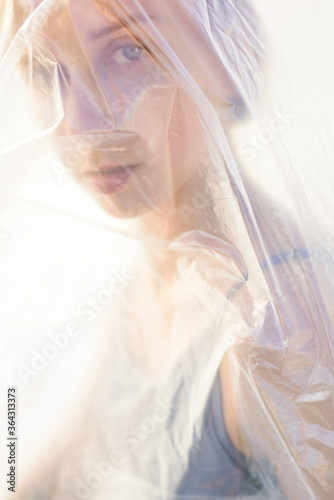 Portrait of beautiful woman in polyethylene wrap. Ecology concept. Unfocused