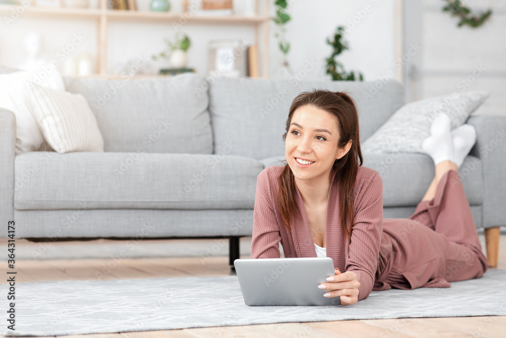 Pensive young woman using digital tablet at home, relaxing on floor Pensive young woman using digital tablet at home, relaxing on floor