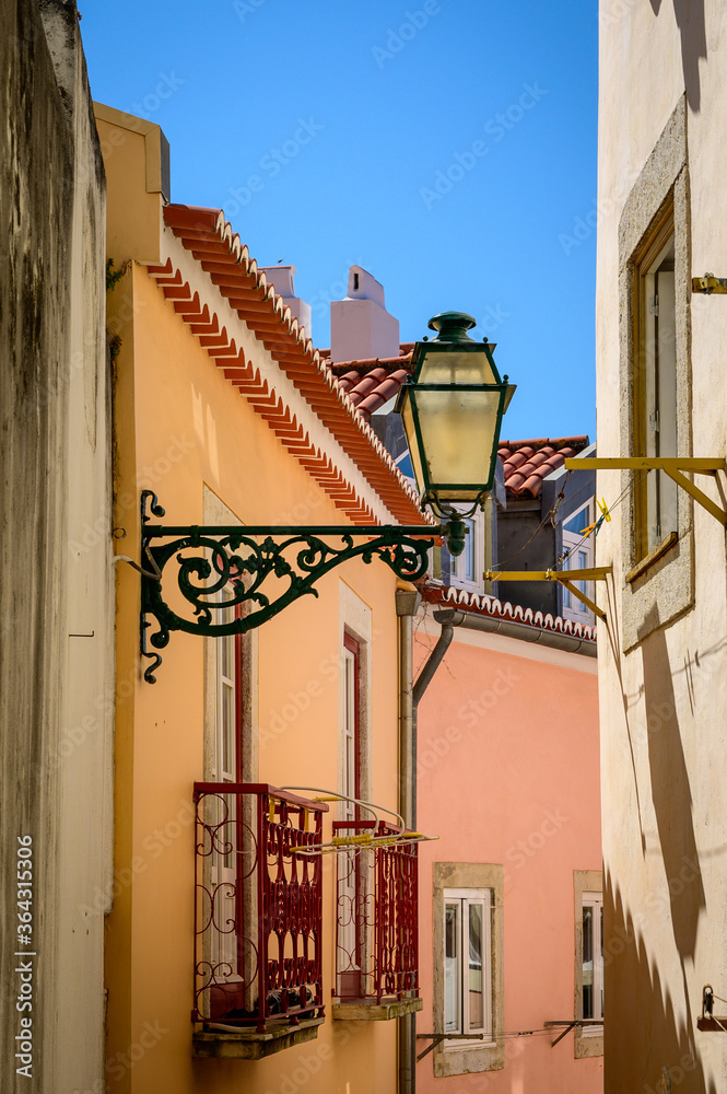 Old street light hanging on the wall in a narrow Lisbon street