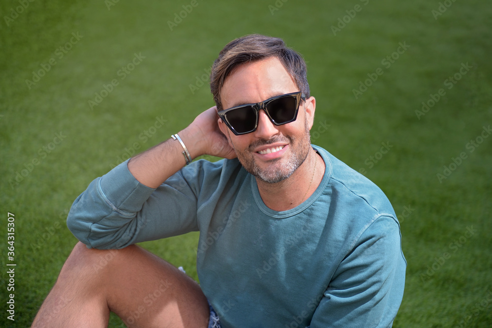 Hombre maduro sonriendo Life Style con gafas de Sol sobre el césped feliz en casa alegría plenitud Hombre maduro sonriendo Life Style con gafas de Sol sobre el césped feliz en casa alegría plenitud