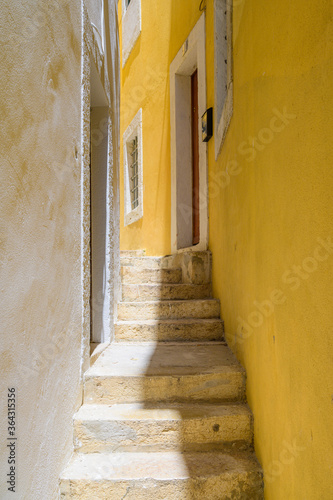 old narrow street with stairs and yellow and white wall and house doors