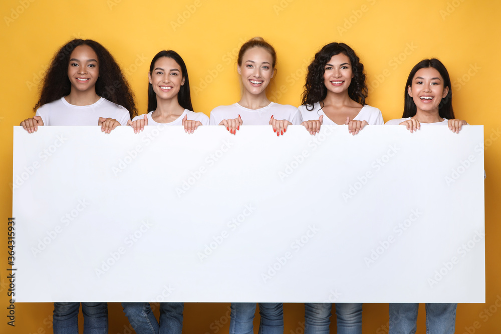 Women Holding Blank Paper Board Advertising Something Over Yellow Background