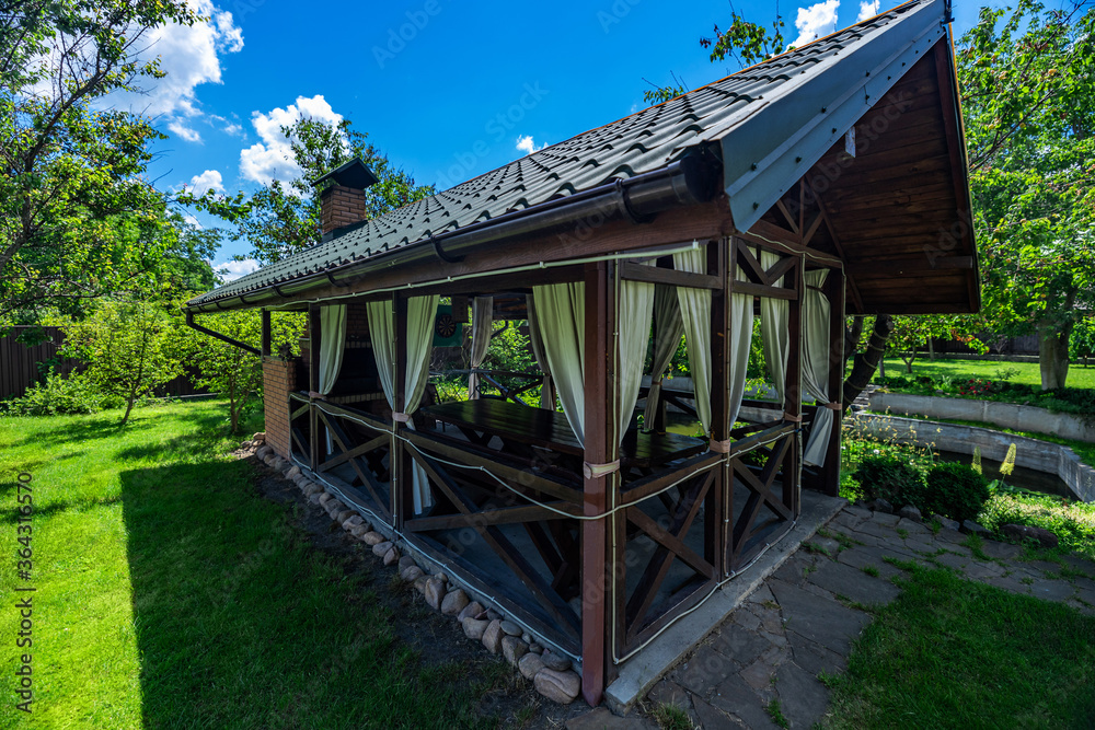 Yard in nature. Beautiful, magnificent view, background and landscape, a panorama of a small wooden gazebo, a veranda in nature, in the hotel, a private villa, on a summer day. Yard in nature. Beautiful, magnificent view, background and landscape, a panorama of a small wooden gazebo, a veranda in nature, in the hotel, a private villa, on a summer day.