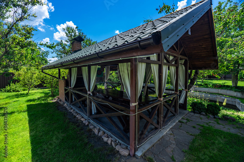 Yard in nature. Beautiful, magnificent view, background and landscape, a panorama of a small wooden gazebo, a veranda in nature, in the hotel, a private villa, on a summer day.