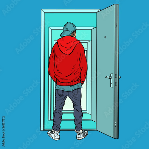 A teenage boy stands on the threshold of an open door