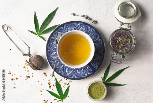 Cannabis infused loose leaf tea overhead photography flat lay. Blue tea cups, cannabis leaves, lavender and marijuana powder. A relaxing and smokeless way to enjoy CBD tea.