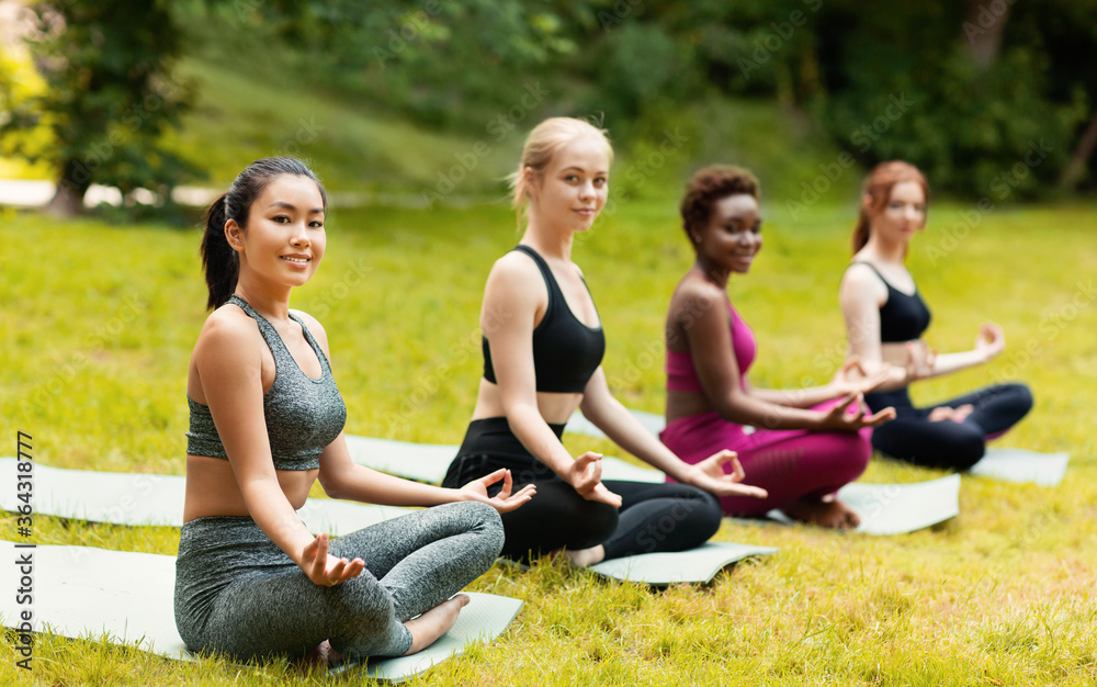 Lovely ladies in sportswear engaged in yoga meditation at beautiful green park, copy space Lovely ladies in sportswear engaged in yoga meditation at beautiful green park, copy space