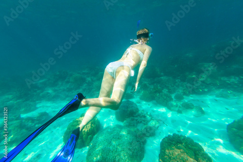 Snorkeler female in Ko Surin Marine National Park, underwater scene. Woman snorkeling activity in white bikini in coral reef of Surin Islands, Andaman Sea, North of Phuket, Phang Nga in Thailand.