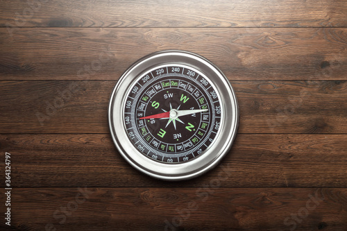 Silver compass on a wooden background top view. The concept of travel, leadership, help. Copy space.