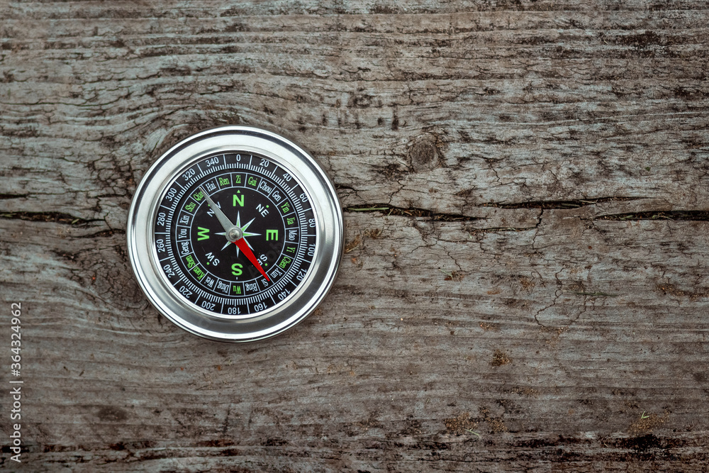 Silver compass on a wooden background top view. The concept of travel, leadership, help. Copy space. Silver compass on a wooden background top view. The concept of travel, leadership, help. Copy space.