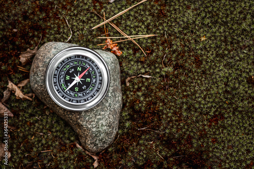 Magnetic compass with a black dial on a stone top view. The concept of travel, finding a path, achievement, hiking, vacation. Copy space.