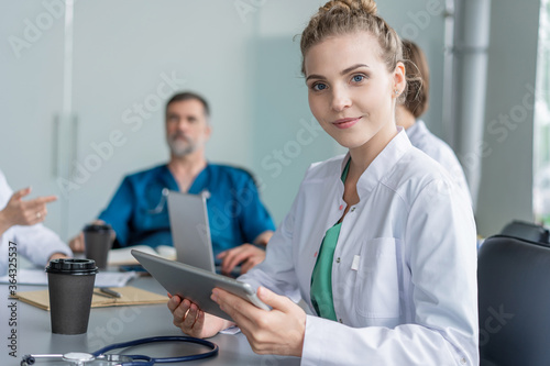 Young female doctor sitting and looking at camera during the meeting in hospital