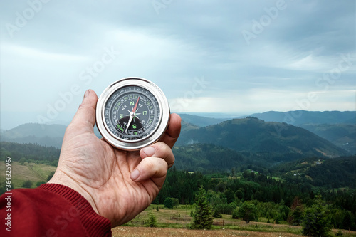 Compass in hand on a background of a landscape of mountains, Close-up. The concept of travel, hiking, vacation. Copy space.