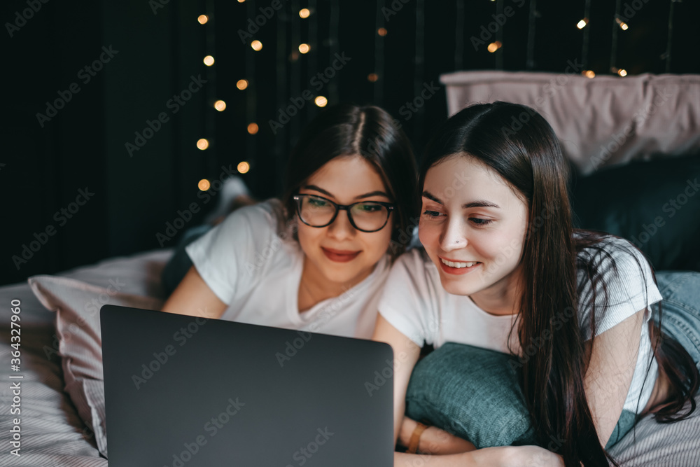 Young beautiful caucasian women's lesbian couple lover, using laptop computer, shopping online together in living room at home in the bed. Concept of LGBT sexuality Young beautiful caucasian women's lesbian couple lover, using laptop computer, shopping online together in living room at home in the bed. Concept of LGBT sexuality