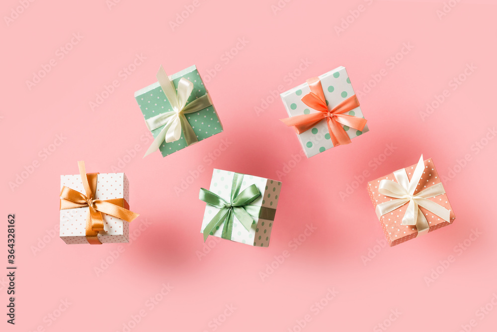 Polka dot pattern gift box with ribbon falling on pink background, levitation Polka dot pattern gift box with ribbon falling on pink background, levitation