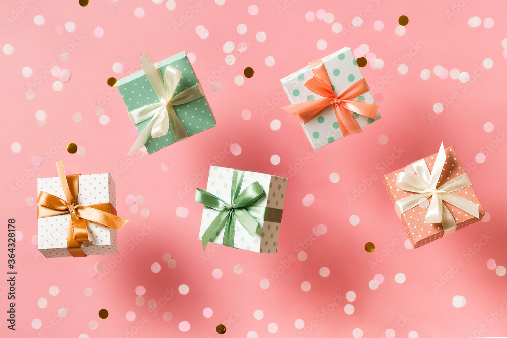 Polka dot pattern gift box with ribbon falling on pink background, levitation Polka dot pattern gift box with ribbon falling on pink background, levitation