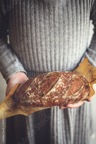 Baked sourdough bread in girl's hands. The bread of sourdough, homemade and natural creation. The sourdough has natural yeast, which makes the food healthier, as well as rich.