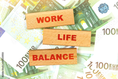 Against the background of euro bills, the text is written on wooden blocks - work life balance