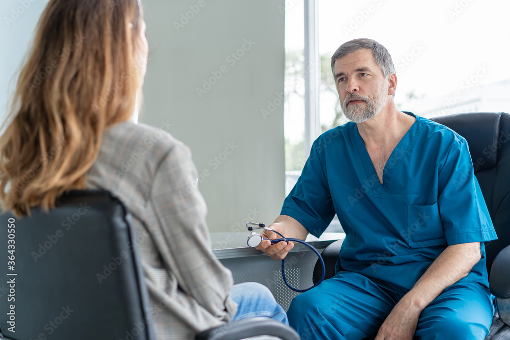 Obraz premium Senior surgeon consults young woman, doctor with patient in medical office.