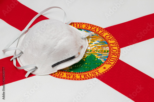 Florida state flag and N95 face mask. Concept of state and local government face covering mandate, order, requirement and social distancing during Covid-19 coronavirus pandemic photo