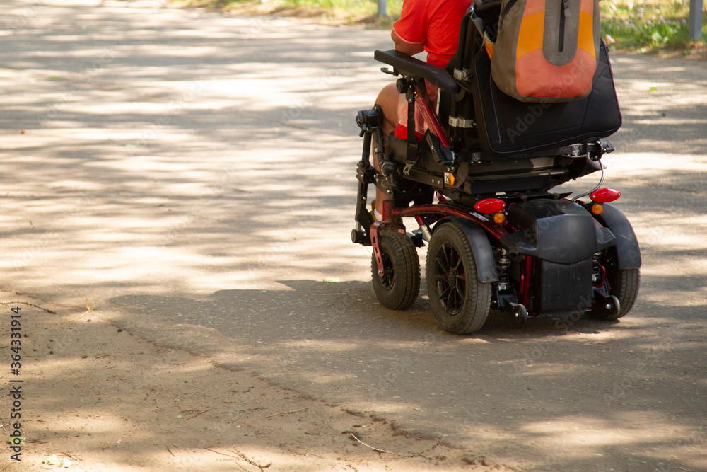 A wheelchair user moves along a city street in summer.
