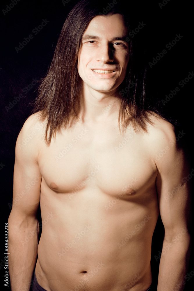 handsome young man with long hair naked torso on black background smiling, lifestyle people concept handsome young man with long hair naked torso on black background smiling, lifestyle people concept