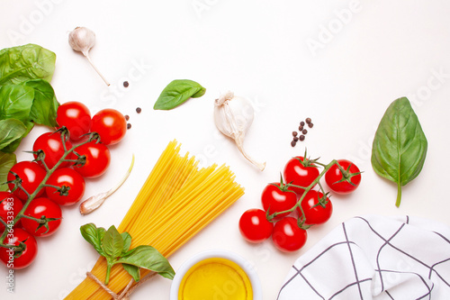 Cooking pasta at home. Vermicelli, cherry tomatoes and basil on a white table