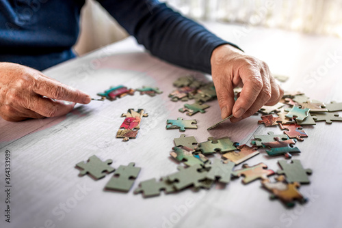 Closeup of the old hands playing with jigsaw puzzles