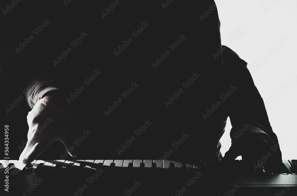 Fototapeta premium silhouette of a pianist on a black and white background, the gloomy figure of a musician in the backlight