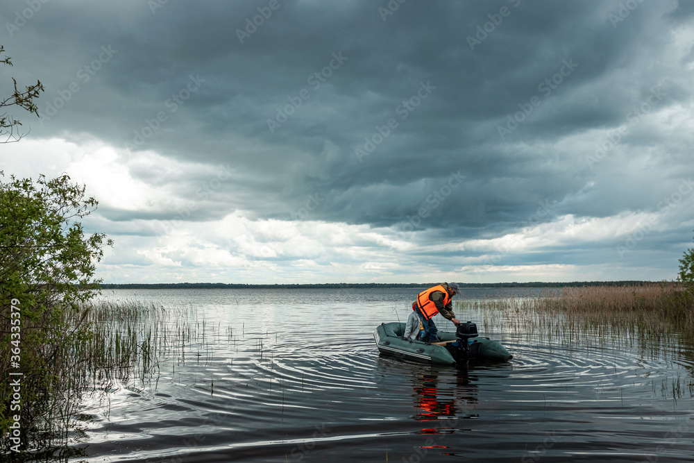 Grandson and grandfather together fish from a boat on the lake. The concept of family, summer vacation, generation. Copy space. Grandson and grandfather together fish from a boat on the lake. The concept of family, summer vacation, generation. Copy space.