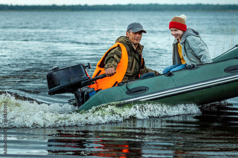 Father and son ride a motor boat on the lake. The concept of family, summer vacation, generation. Copy space.