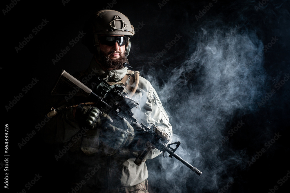portrait of a soldier in a military uniform with a weapon on a dark black background, a commando in military ammunition, the fight against terrorism