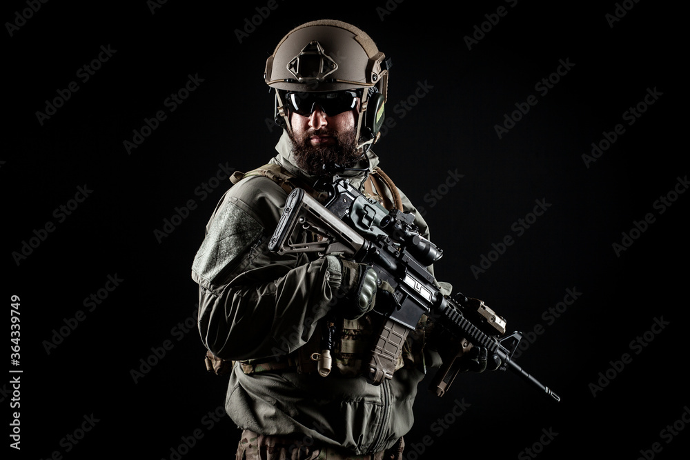 American commando in a military uniform with a weapon looks at copy space, a marine on a dark background, a member of the elite troops, war concept