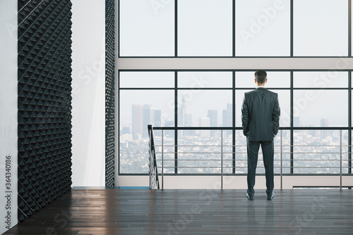 Businessman standing in hall interior with panoramic city view.