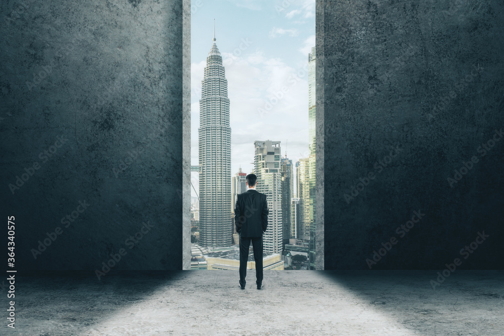 Businessman stands in the doorway and looking on modern city