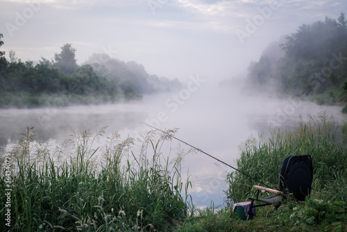 Landscape. River at dawn with foggy haze. Fishing gear on the shore. Highchair and spinning for fishing.
