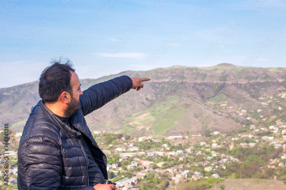 man standing on the top of the mountain exploring the mountains and pointing the landscape