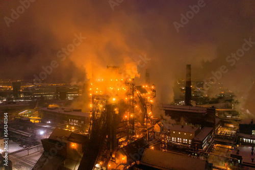 Night top view of steel plant at night with smokestacks and fire blazing out of the pipe