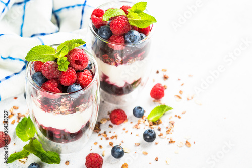 Parfait with granola, jam and fresh berries in the glass jar.