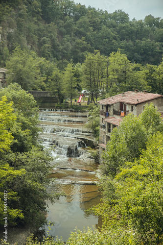 RUPIT and PRUIT, SPAIN - JULY, 2020: Medieval town of Rupit, with river and waterfall between the houses and the green forest