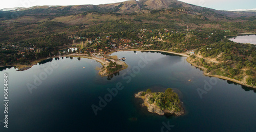 Tourism. The lake at sunset. Aerial view of the tranquil village Pehuenia. The bay, harbor, island, forest and mountains at nightfall.