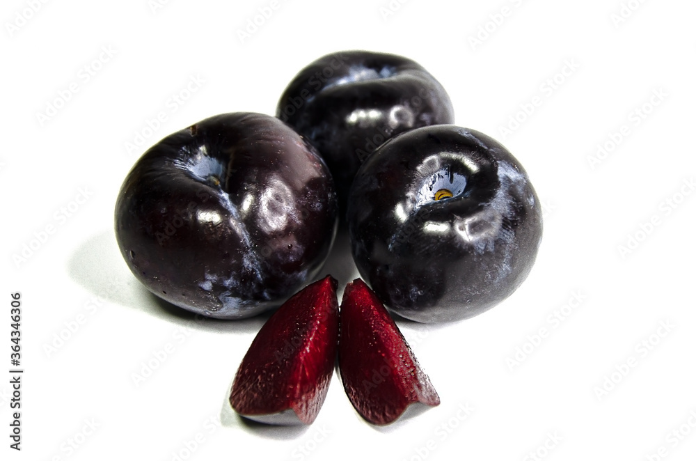 Three large red plums and two juicy slices of plum isolated on a white background. Three large red plums and two juicy slices of plum isolated on a white background.