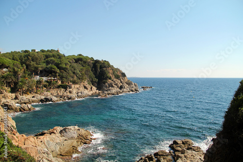spain coast of the sea. Beautiful view of rocks with green pine trees and blue sea with waves under sky. Mediterranean Sea.