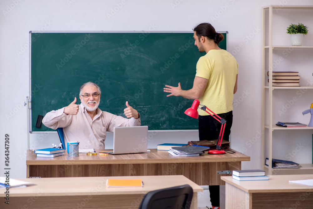 Old teacher and young male student in the classroom Old teacher and young male student in the classroom