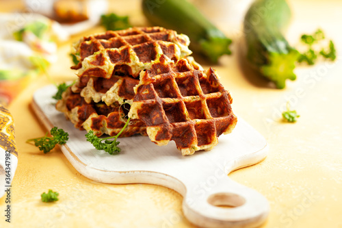 Homemade low carb zucchini waffles on white wooden board on yellow background. Concept of keto diet food.