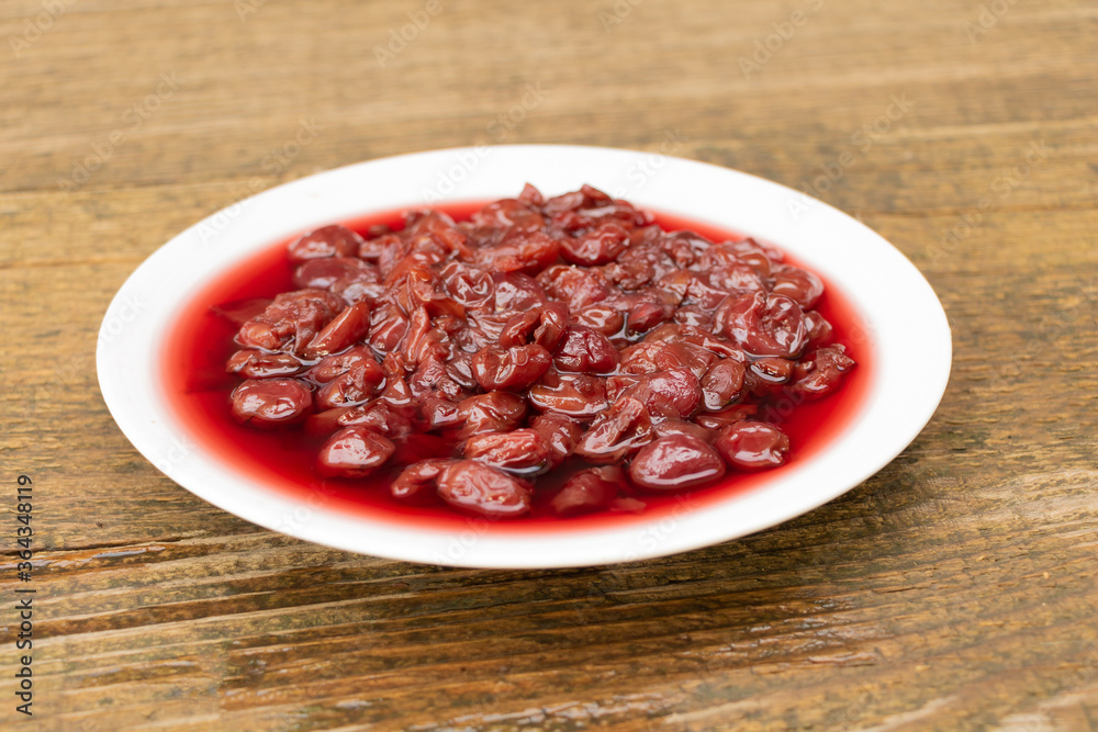 A plate full of cherry jam on wooden background A plate full of cherry jam on wooden background