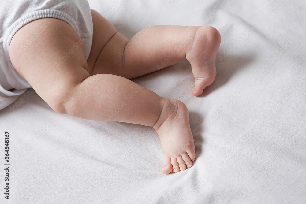 Baby lying on bed low section