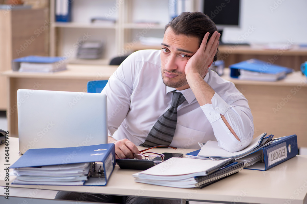 Young male employee unhappy with excessive work Young male employee unhappy with excessive work