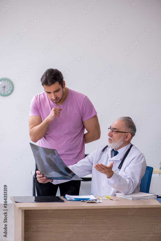 Obraz premium Old doctor radiologist examining young male patient